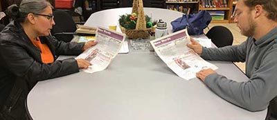 Two adults sitting at a table reading at a Reading Works literacy program.